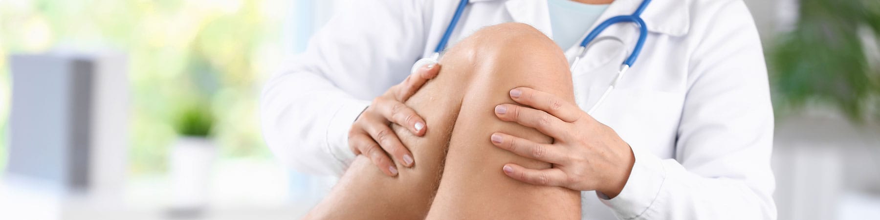 An orthopedic doctor examines a patient's knee during evaluation for joint pain, injury treatment, or advanced orthopedic services, including sports medicine care.